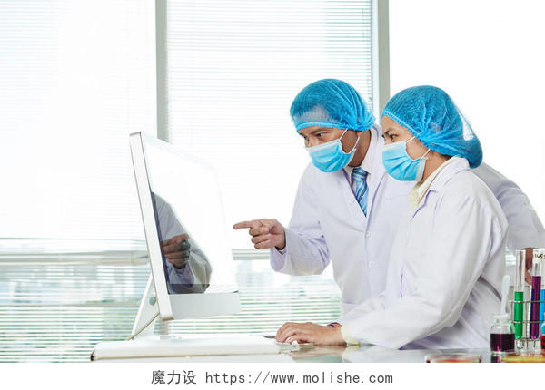 戴口罩的越南实验室工作人员讨论电脑屏幕上的研究细节